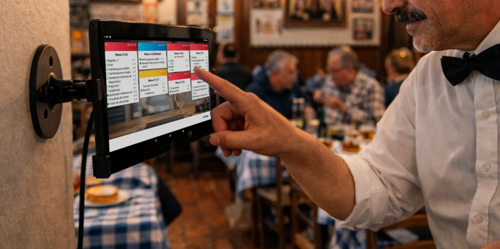 Mozo cargando una comanda en una tablet del salón